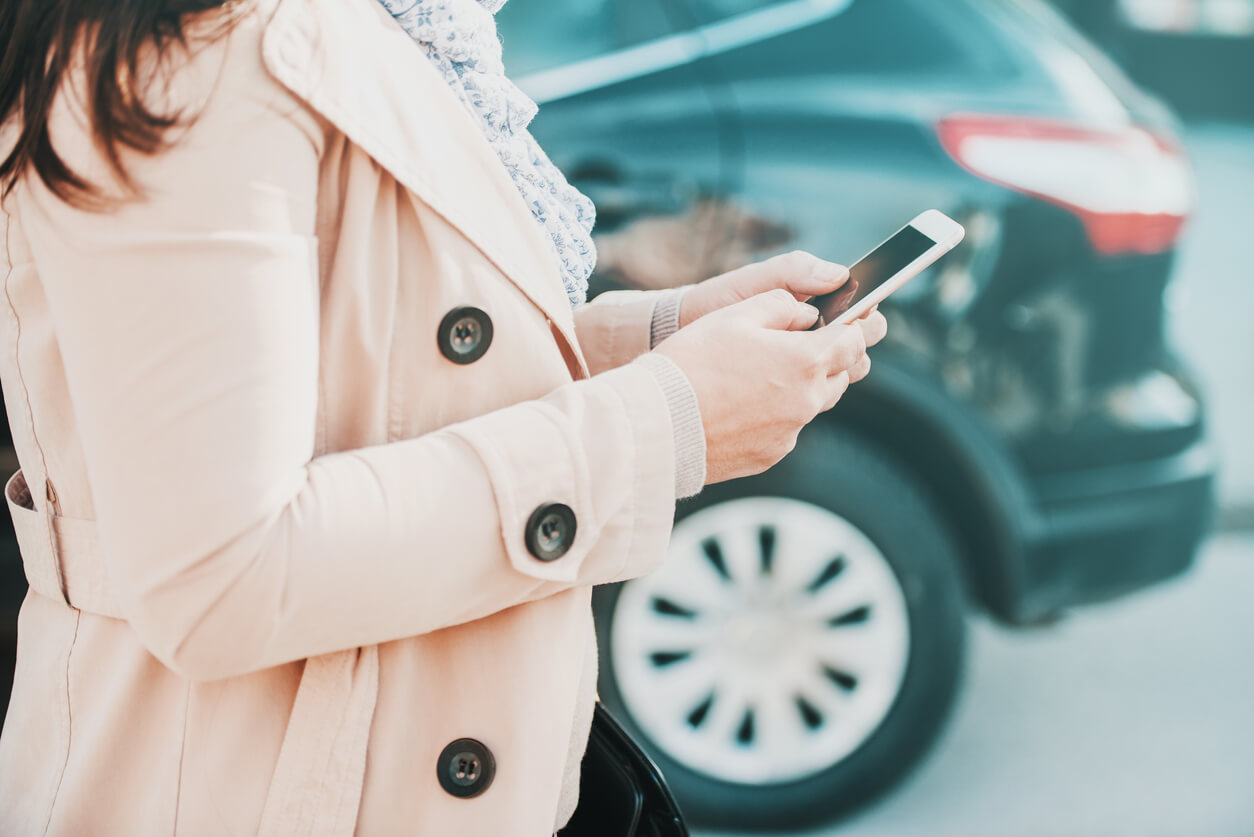 Woman using her smartphone to report a parking lot accident.