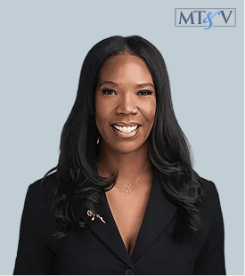 Professional portrait of a smiling Black woman with long black hair wearing a black blazer, against a blue background; MTSV logo in the top-right corner. Chimere-new  Miller, Tischler & Vislosky, P.C. Chimere-new  Miller, Tischler & Vislosky, P.C.