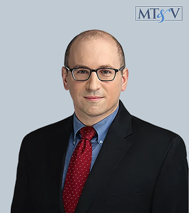 Professional headshot of a bald man with glasses wearing a dark suit, blue shirt, and red tie against a light blue background, with an MTSV logo in the top-right corner. David  Miller, Tischler & Vislosky, P.C. David  Miller, Tischler & Vislosky, P.C.